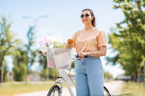 Image of woman with food and flowers in bicycle basket