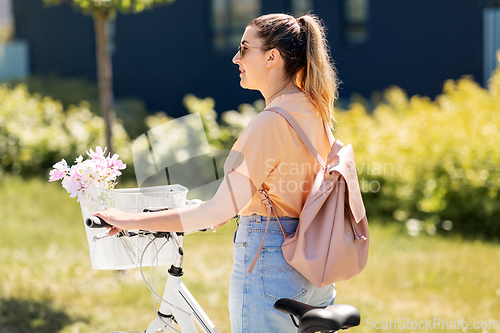 Image of woman with flowers in bicycle basket in city