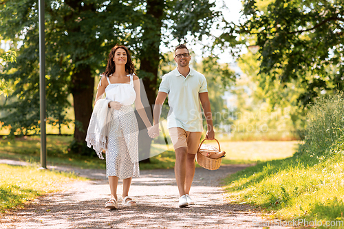 Image of happy couple with picnic basket at summer park