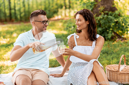 Image of happy couple with wine having picnic at park