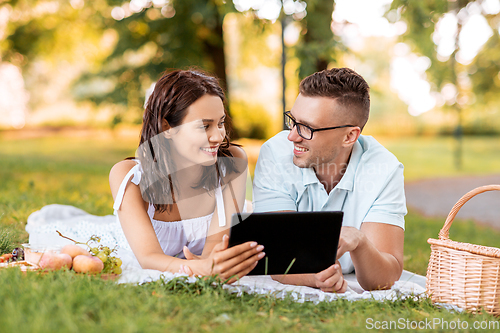 Image of happy couple with tablet pc at picnic in park