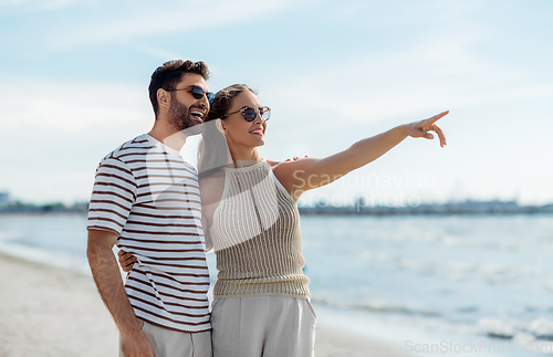 Image of happy couple pointing finger on summer beach