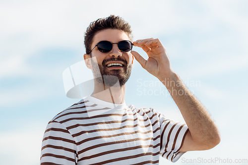 Image of smiling young man in sunglasses over sky