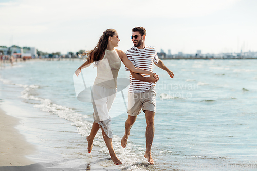 Image of happy couple running along summer beach