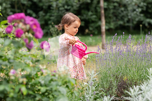 Image of happy baby girl with watering can in summer garden