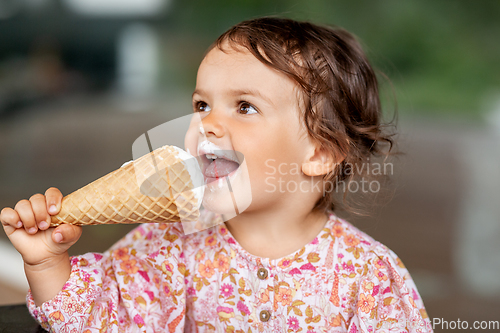 Image of happy little baby girl eating ice cream