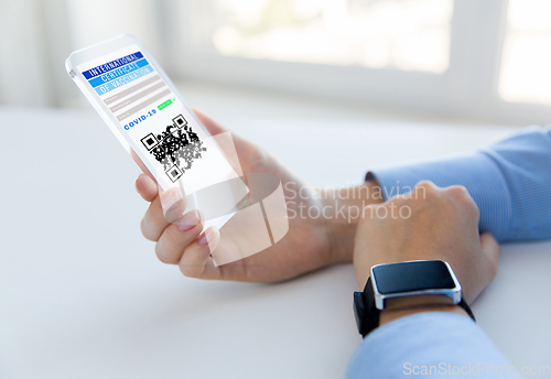 Image of hands with virtual immunity passport on smartphone