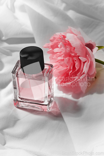 Image of bottle of perfume and flower on white sheet