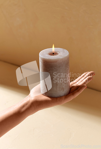 Image of hand holding burning aroma candle on palm