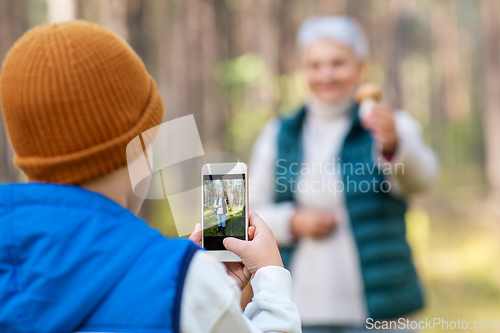 Image of grandson photographing grandmother with mushroom