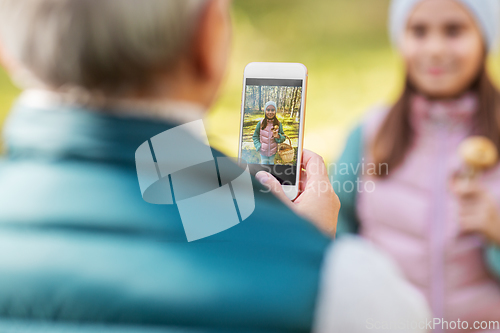 Image of grandma photographing granddaughter with mushrooms