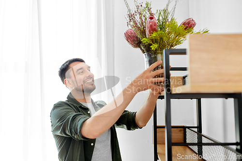 Image of man decorating home with flowers in vase