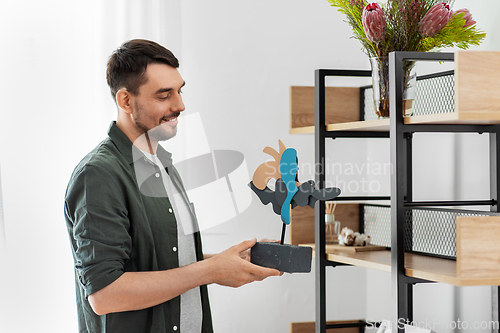 Image of man decorating home with art in frame