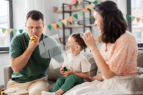 Image of happy family with gifts and party blowers at home