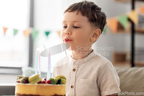 Image of happy little boy blowing candles on birthday cake