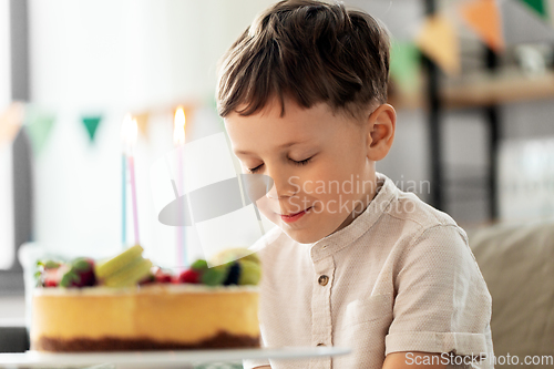 Image of happy little boy blowing candles on birthday cake