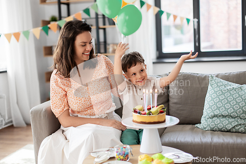 Image of happy mother and son with birthday cake at home