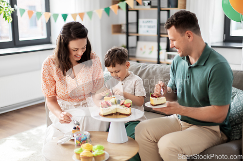 Image of happy family eating birthday cake at home party