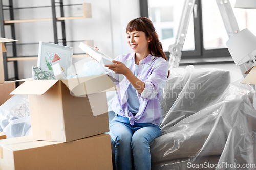 Image of happy woman unpacking boxes and moving to new home