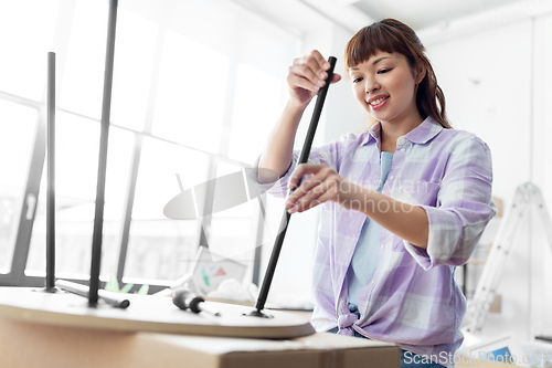 Image of happy woman assembling coffee table at new home