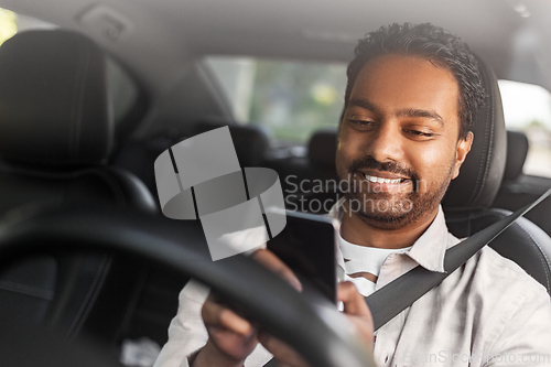 Image of smiling indian man in car using smartphone