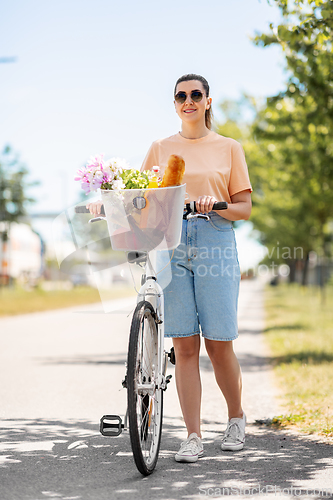Image of woman with food and flowers in bicycle basket