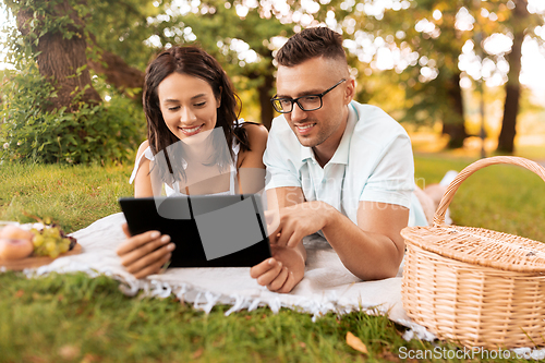 Image of happy couple with tablet pc at picnic in park