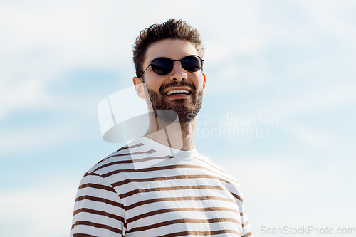 Image of smiling young man in sunglasses over sky