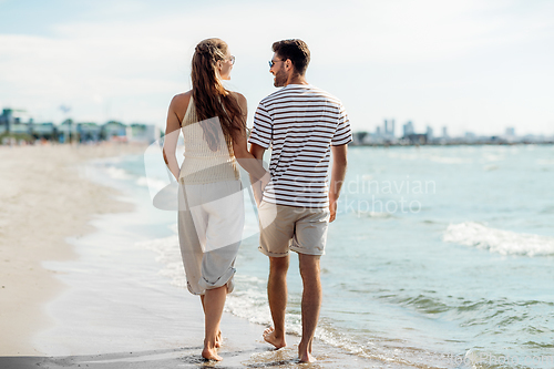 Image of happy couple walking along summer beach