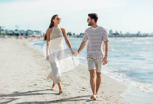 Image of happy couple walking along summer beach