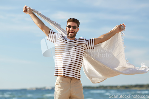 Image of smiling man in sunglasses with blanket on beach