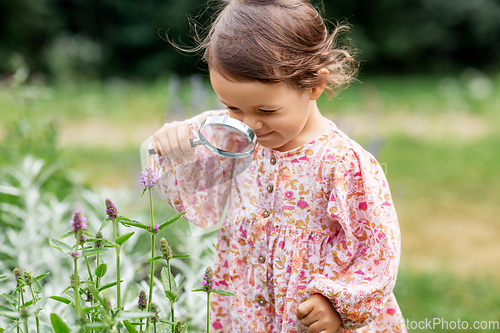 Image of baby girl with magnifier looking at garden flowers