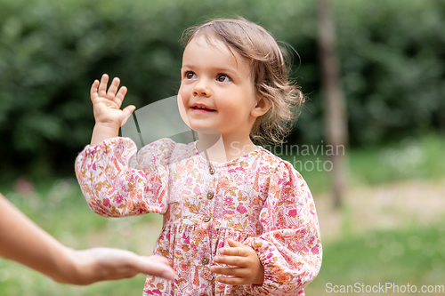 Image of happy smiling baby girl giving hand to adult