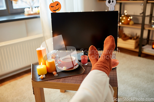 Image of young woman watching tv at home on halloween