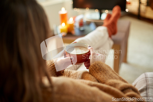 Image of woman watches tv and drinks cocoa on halloween