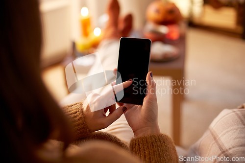 Image of woman using smartphone at home on halloween