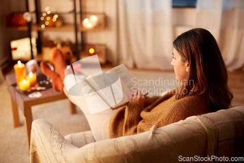 Image of young woman reading book at home on halloween