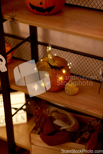 Image of halloween pumpkin with garland lights on shelf