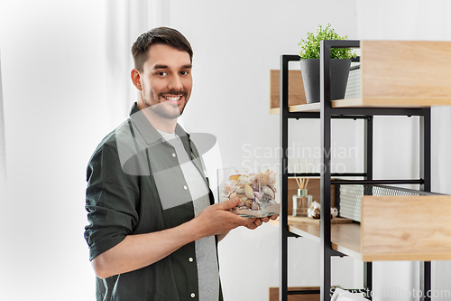 Image of man decorating home with seashells in vase