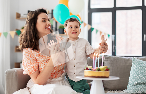 Image of happy mother and son with birthday cake at home