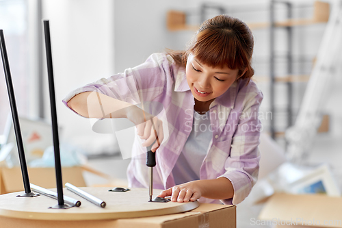 Image of happy woman assembling coffee table at new home