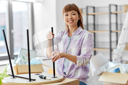 Image of happy woman assembling coffee table at new home