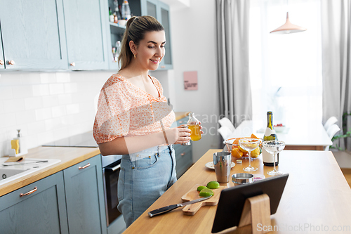 Image of woman with tablet pc making cocktails at kitchen