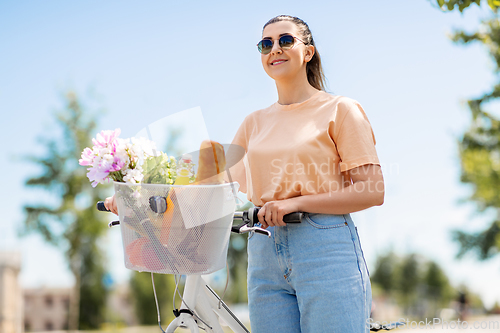 Image of woman with food and flowers in bicycle basket