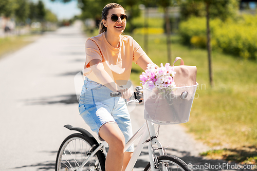 Image of woman with flowers in bicycle basket in city