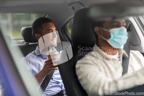 Image of male passenger with coffee and car driver in mask
