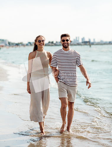 Image of happy couple walking along summer beach