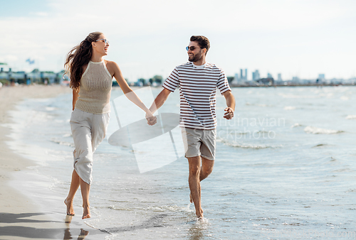 Image of happy couple running along summer beach