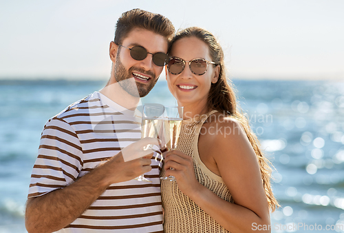 Image of happy couple drinking champagne on summer beach