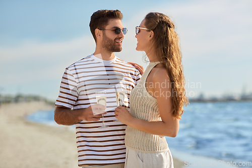 Image of happy couple drinking champagne on summer beach